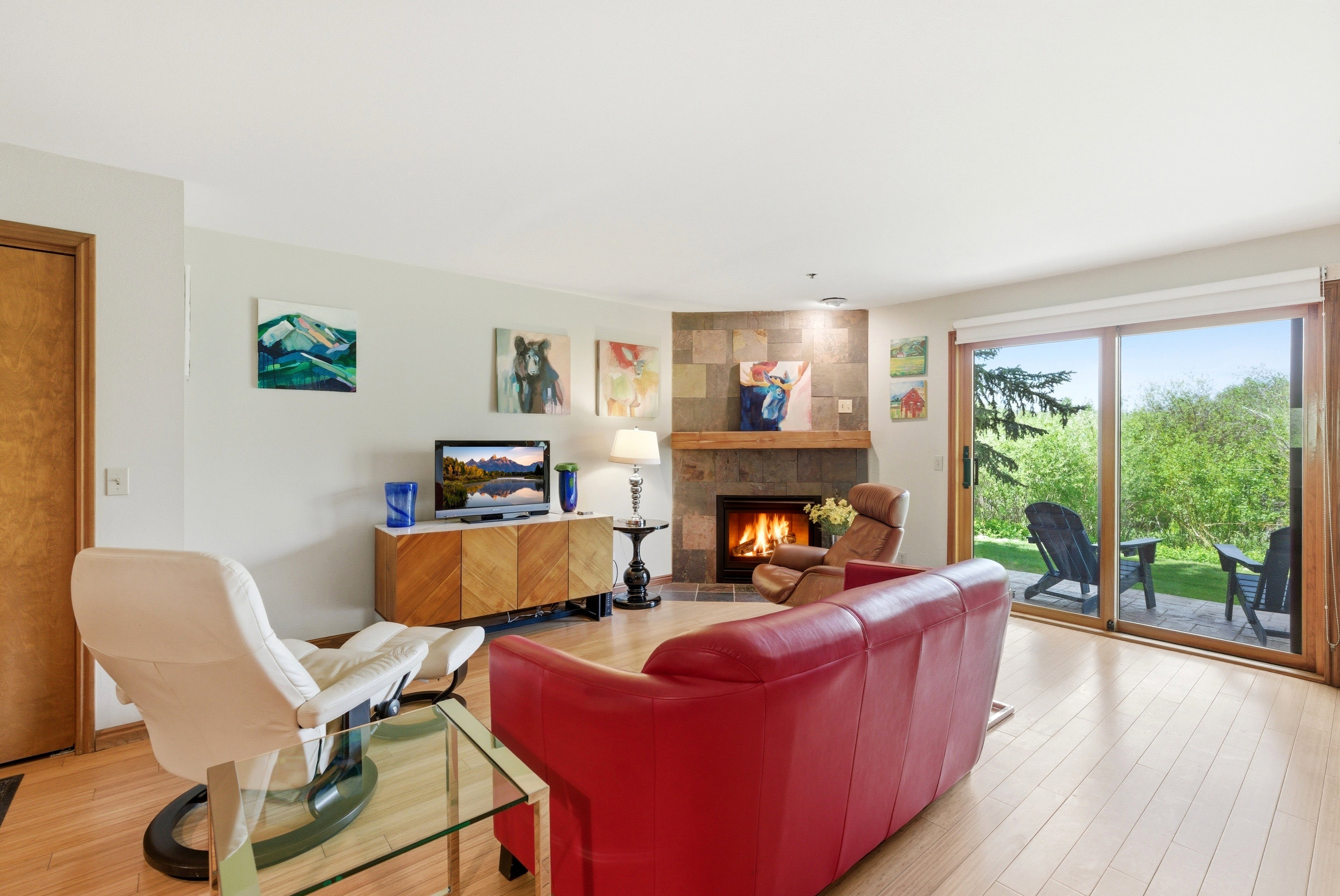 Living area featuring light wood-finish flooring and a stone-clad fireplace with a wood mantle