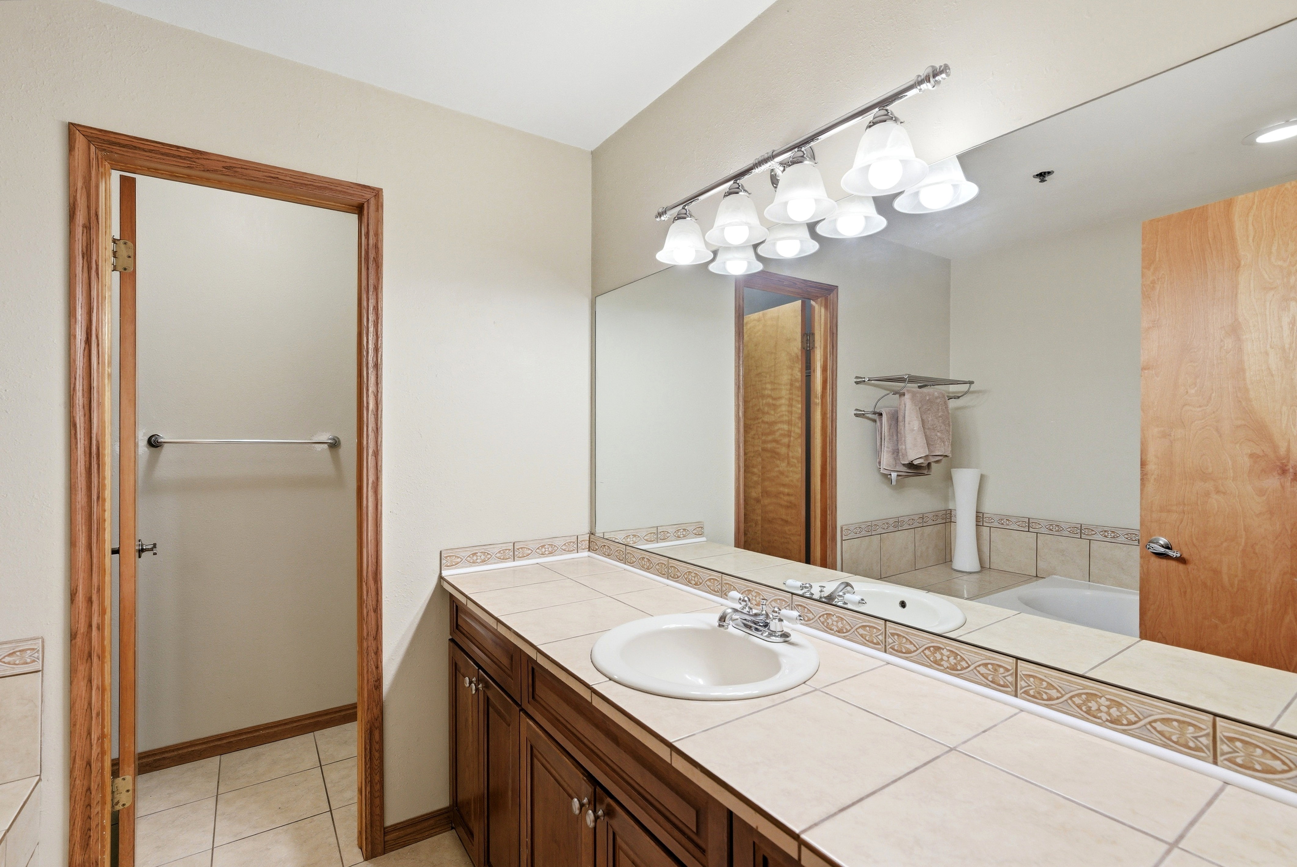 Bathroom vanity with a tile countertop, integrated sink, and wood cabinetry