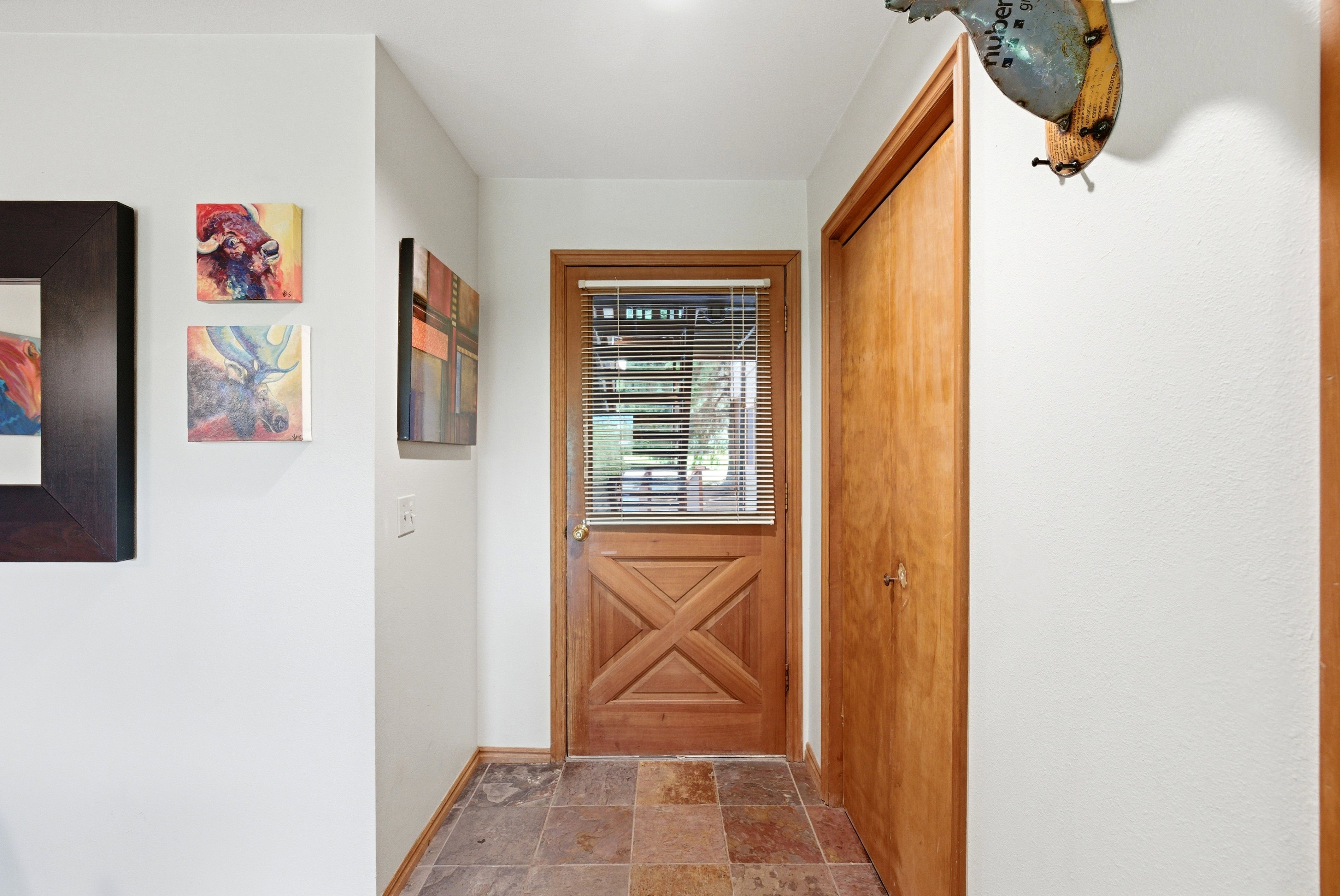 Wood-paneled Dutch door with integrated blinds, complemented by multi-tone stone tile flooring
