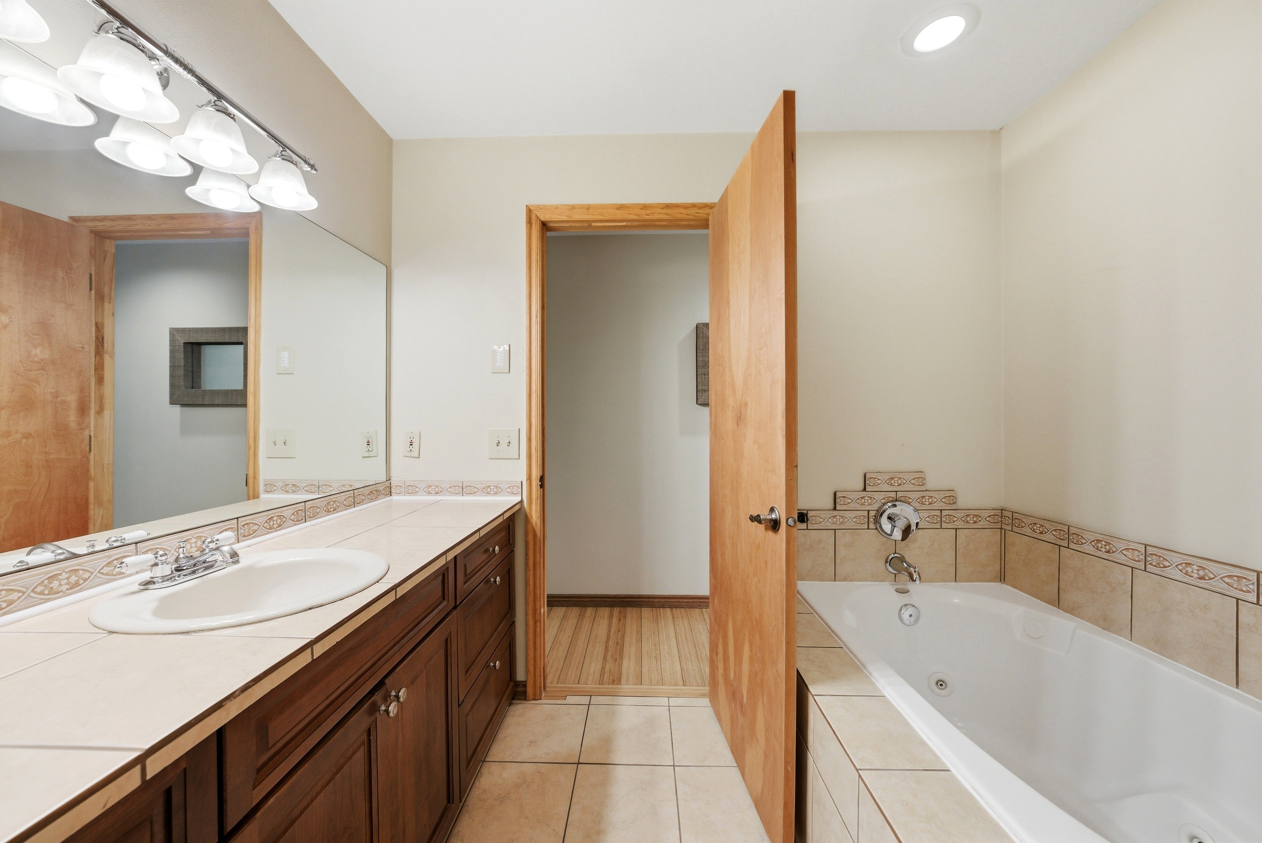 Bathroom featuring a spacious vanity with integrated sink, a large mirror, and a tiled countertop