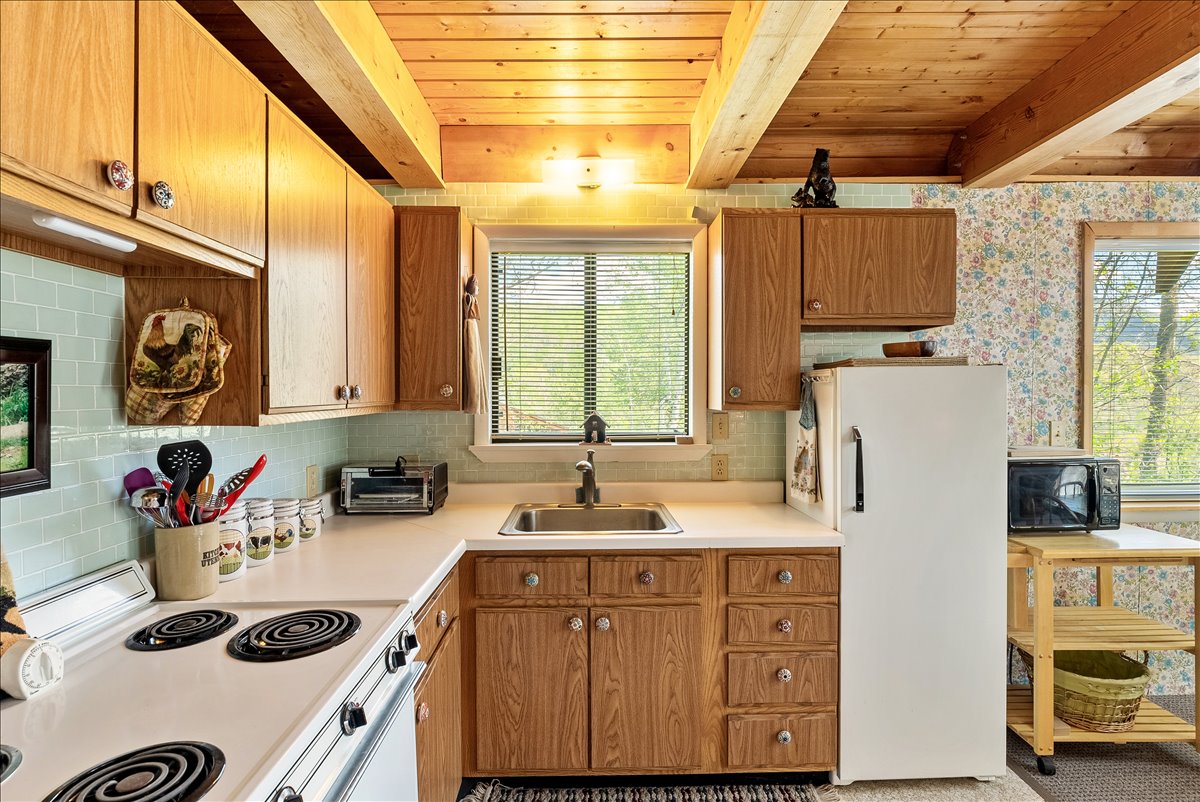 Kitchen featuring wood-finish cabinetry, a white electric range, and a stainless steel sink