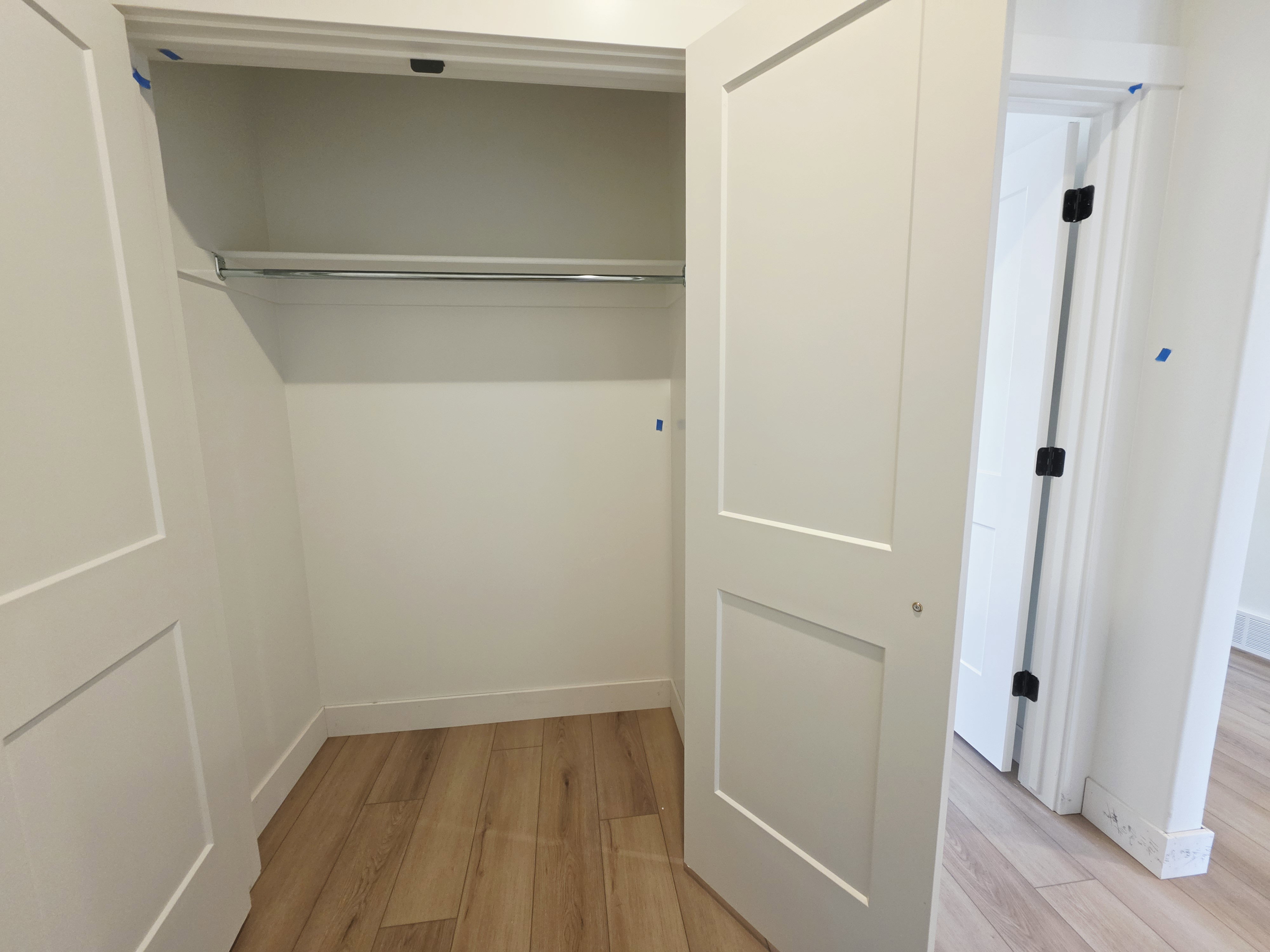 Closet space featuring a built-in hanging rod, light wood-finish flooring, and white trim