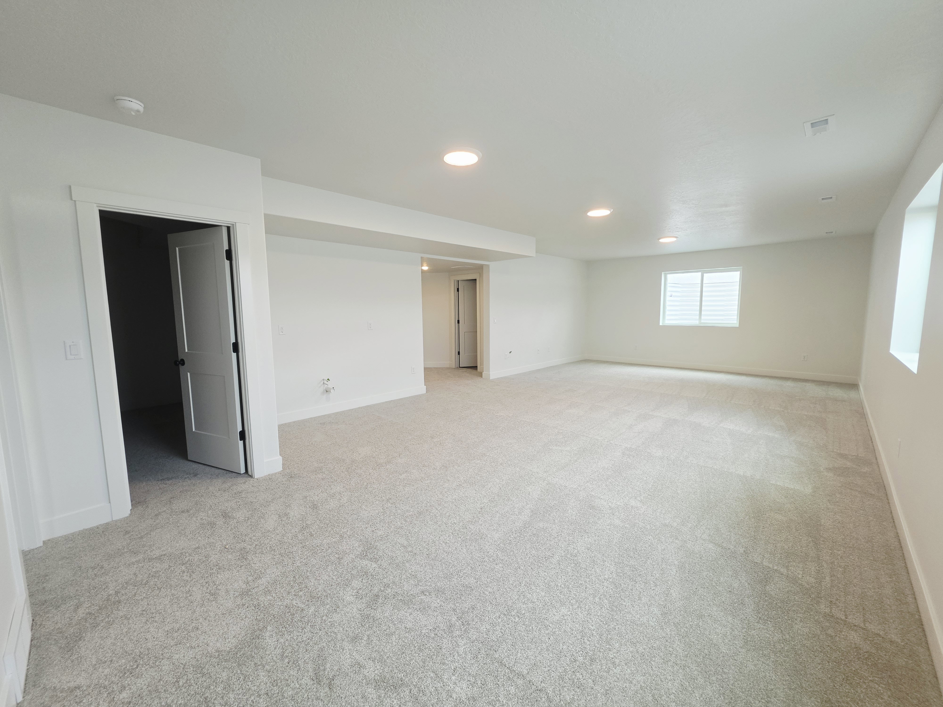 Spacious room featuring light-colored carpeting, white walls, and recessed lighting