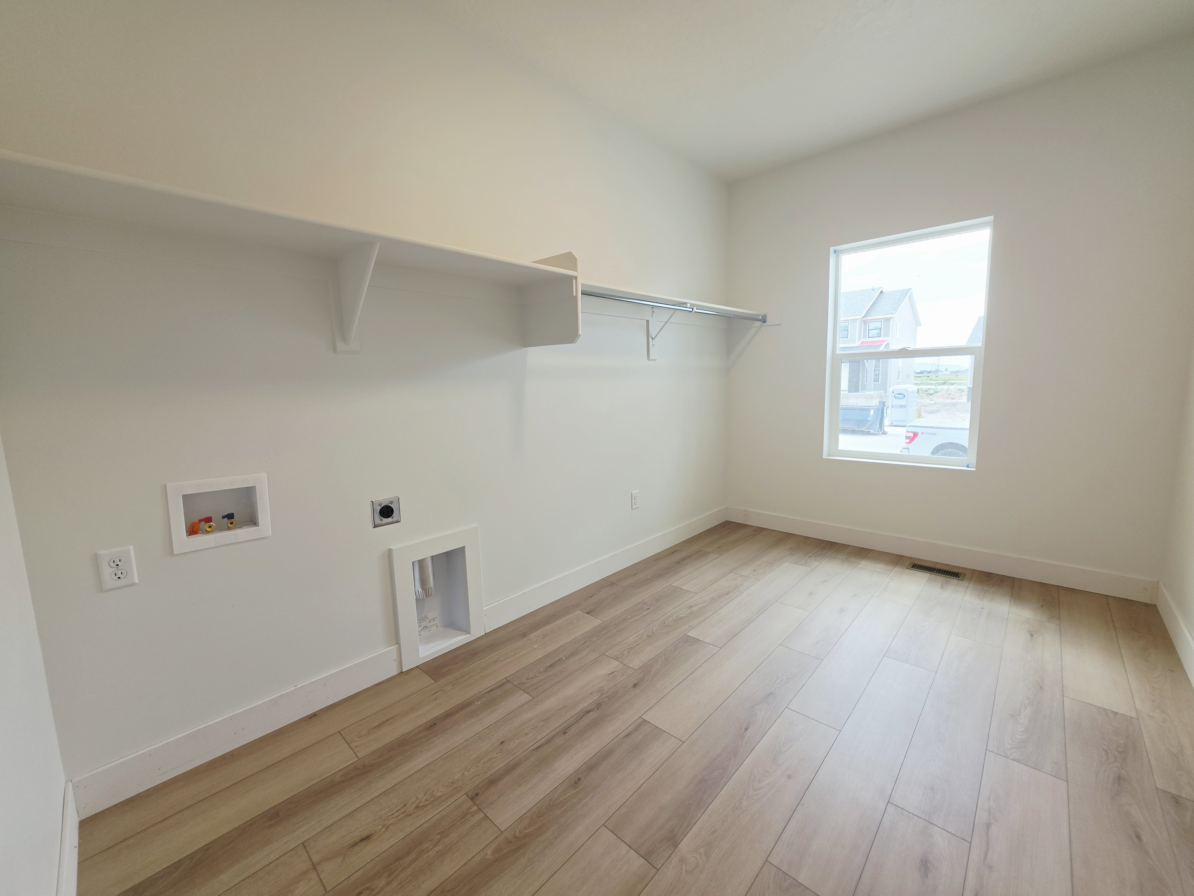 Dedicated utility space featuring wood-finish flooring, white walls, and a single window