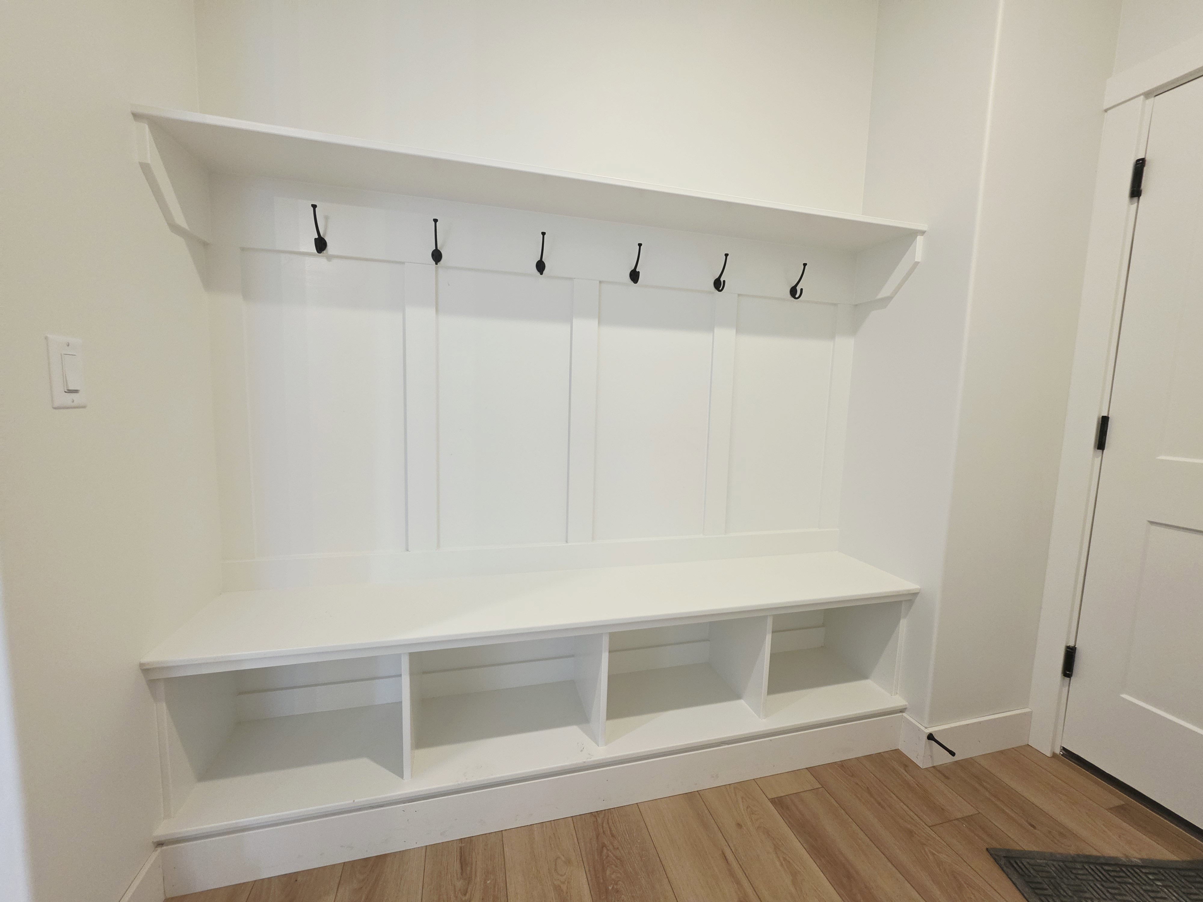 Built-in hall tree featuring a white finish, panel backing, upper shelf, and five matte black coat hooks
