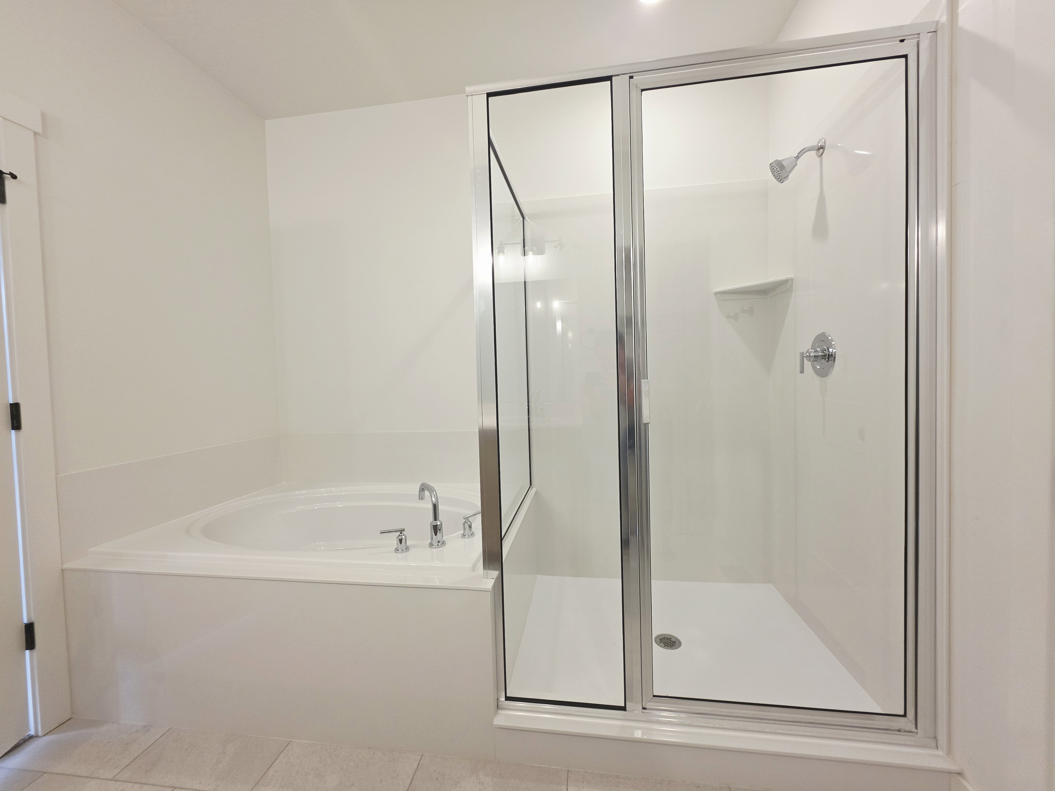Bathroom featuring a built-in soaking tub with chrome fixtures, and a separate glass-enclosed shower with a white surround and chrome showerhead