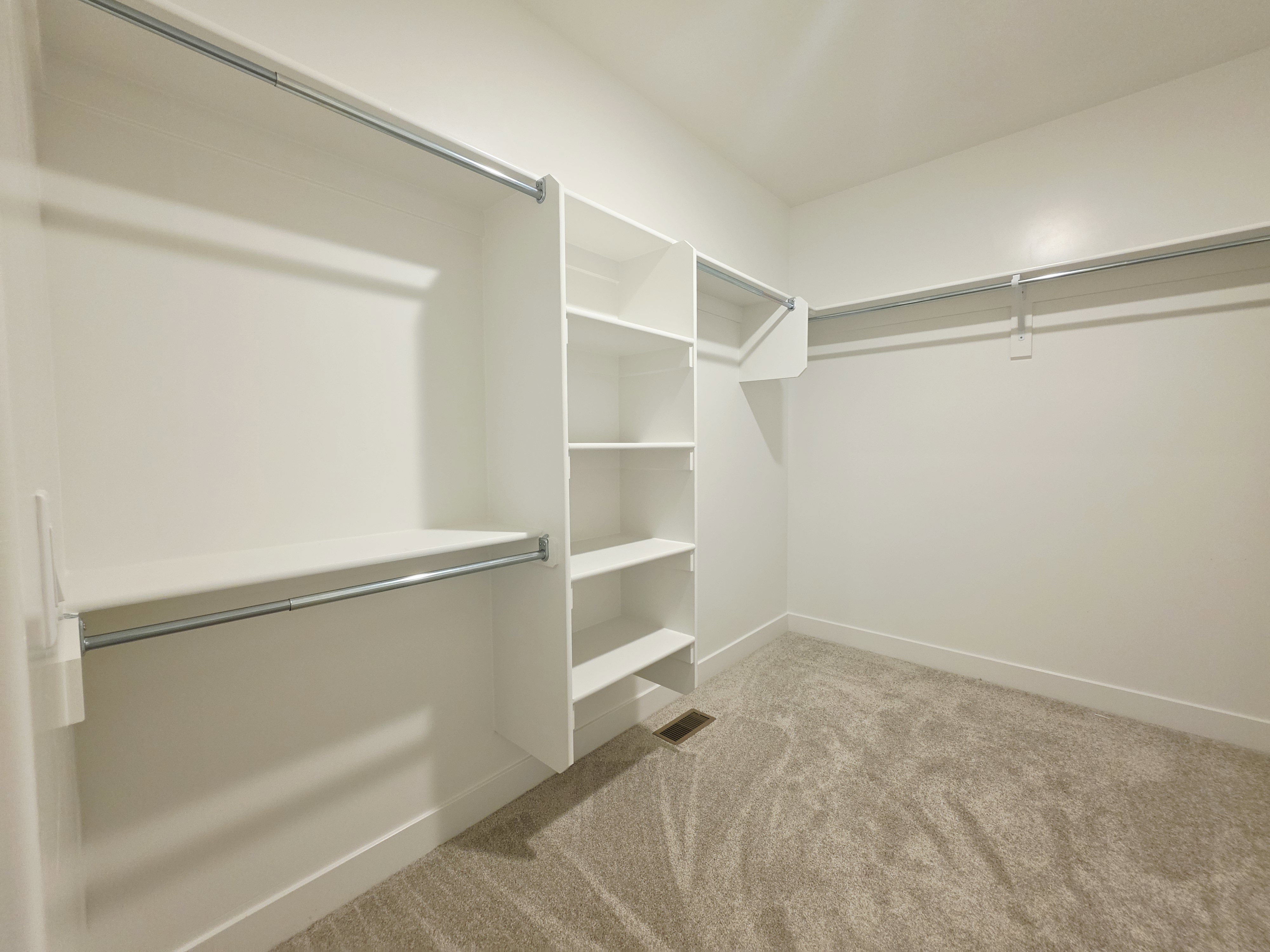 Walk-in closet featuring built-in shelving, multiple hanging rods, and neutral-toned carpeting