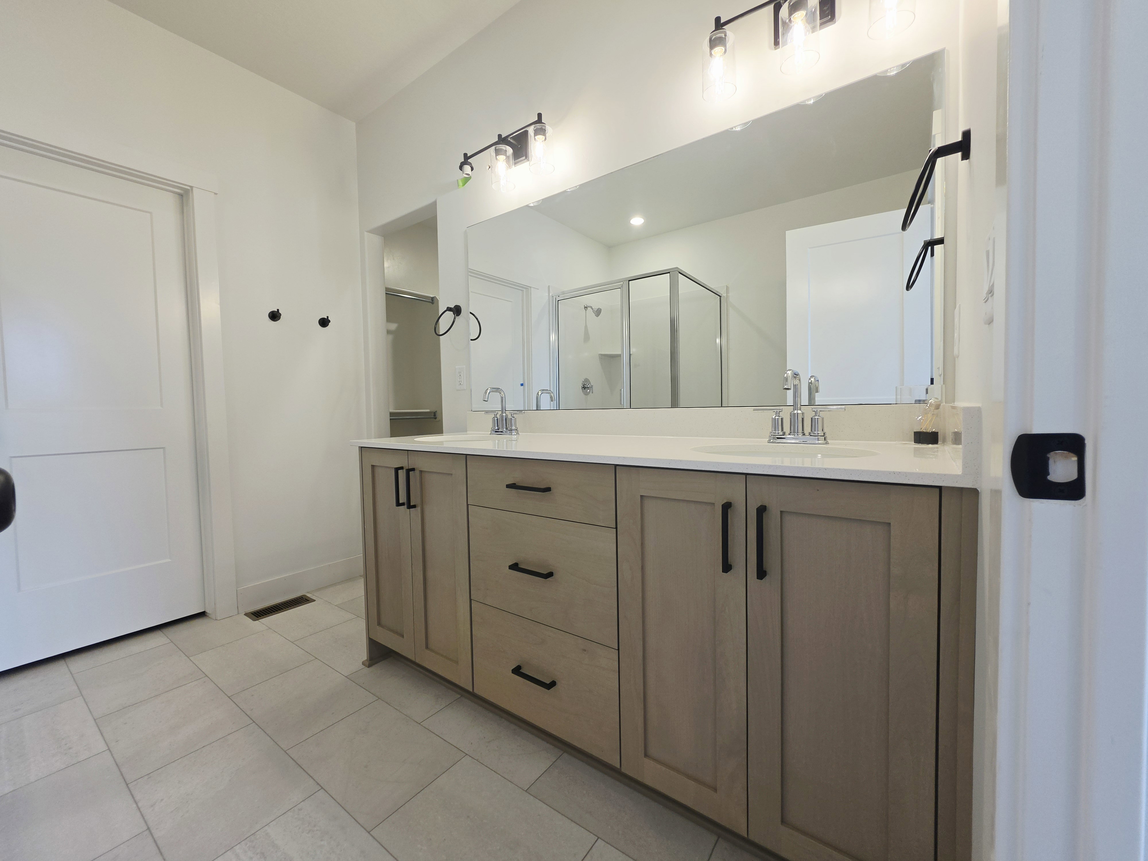 Double vanity with light wood-finish cabinetry, white countertop, and dual sinks