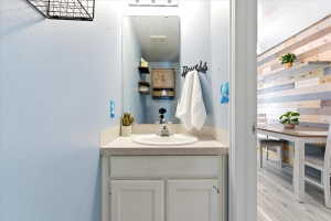 Bathroom vanity featuring a single basin sink, light-colored countertop, and storage cabinetry
