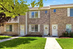 Brick townhome exterior featuring two stories, white window shutters, and a well-maintained lawn with a paved walkway