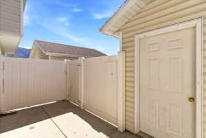 Private patio area with concrete flooring, framed by a beige privacy fence and a four-panel exterior door