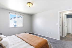 Bedroom featuring a large window, light gray walls, dark gray carpeting, and a built-in ceiling light fixture