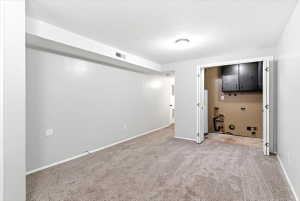 Carpeted room featuring light gray walls, a recessed ceiling light, and a bi-fold door utility closet with overhead cabinetry