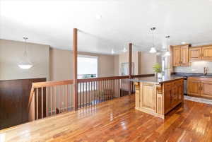 Hardwood flooring throughout the upper level, featuring a kitchen island with pendant lighting
