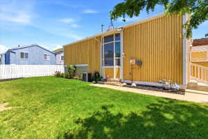 Spacious rear yard featuring an expansive lawn, white picket fencing, and mature landscaping