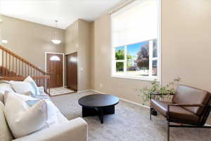 Entryway and living area featuring high ceilings, a full-lite entry door, a staircase with wood railing, broad windows, and wall-to-wall carpeting