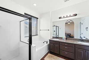 Spacious bathroom featuring a dual vanity with a granite-style countertop, dark wood-finish cabinetry, and undermount sinks
