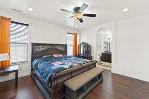 Spacious bedroom featuring dark wood-finish flooring, recessed lighting, and a ceiling fan with integrated light fixture
