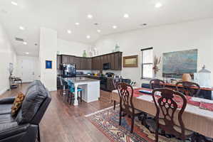 Open-concept living area featuring wood-finish flooring, recessed lighting, and a vaulted ceiling
