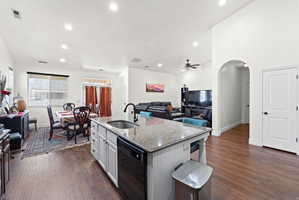 Spacious open-concept interior featuring wood-finish flooring, a kitchen island with stone countertop, and recessed lighting