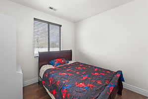 Bright room featuring a window with horizontal blinds, wood-finish flooring, white baseboards, and light-toned walls