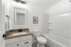Bright bathroom with white vanity cabinetry, integrated sink, and bronze-finish fixtures