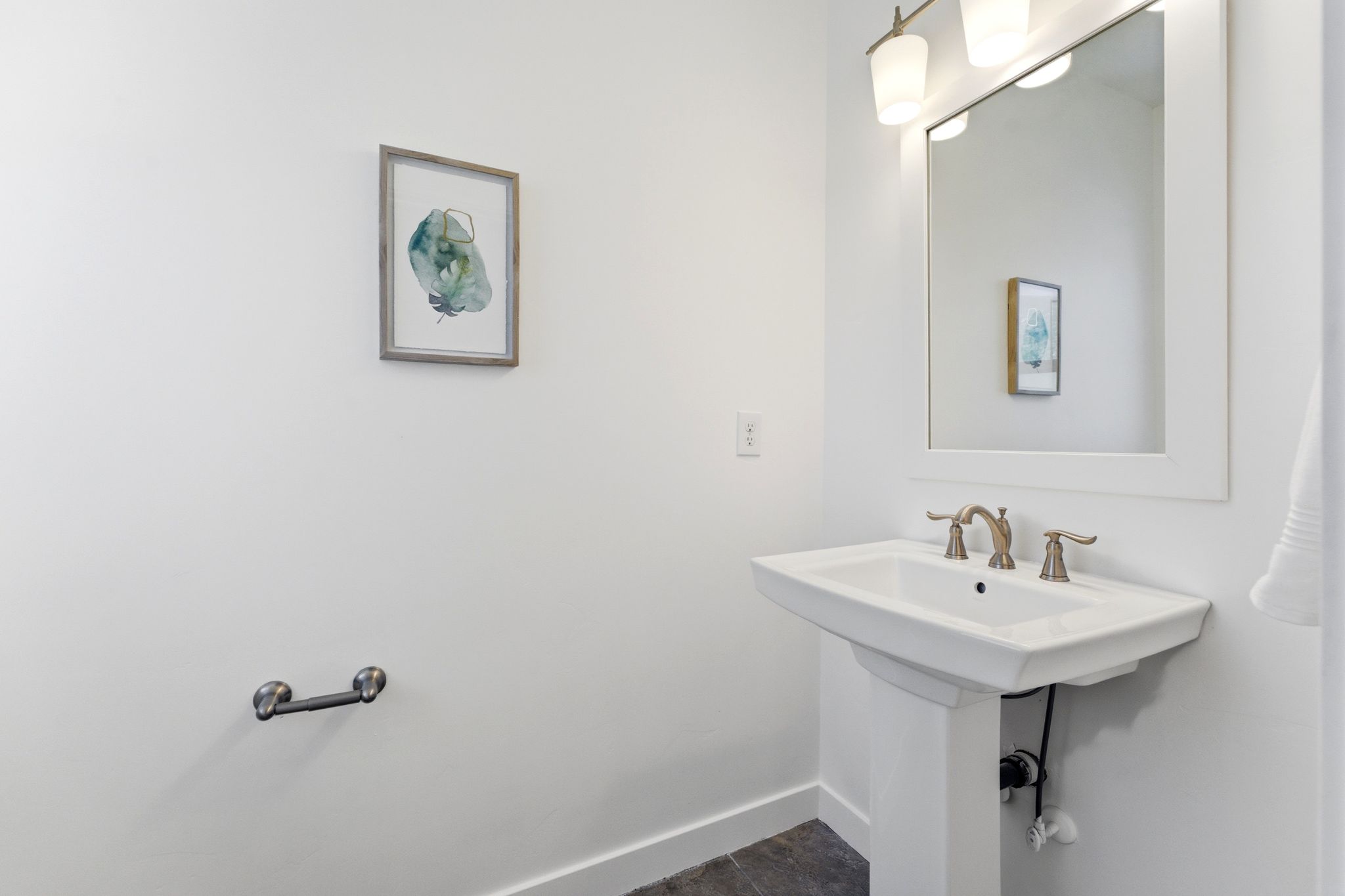 Pedestal sink with bronze-finish faucet, rectangular framed mirror, and two-light vanity fixture