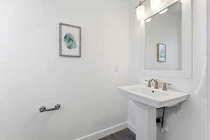 Pedestal sink with bronze-finish faucet, rectangular framed mirror, and two-light vanity fixture