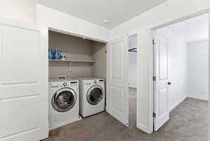 Dedicated laundry closet with front-loading washer and dryer, featuring overhead shelving