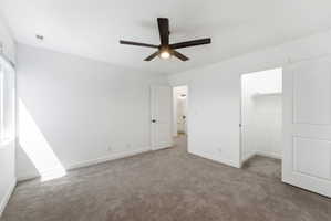 Neutral carpeted room with a modern ceiling fan, white walls, and a window
