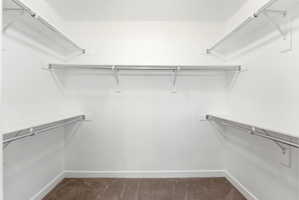 Walk-in closet featuring white painted walls, a plush brown carpet, built-in shelving, and metal hanging rods