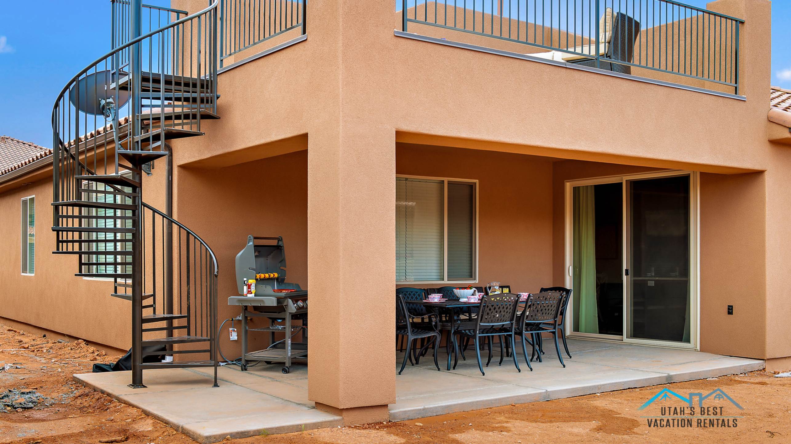 Two-story stucco exterior featuring a spiral staircase providing access to the upper-level balcony