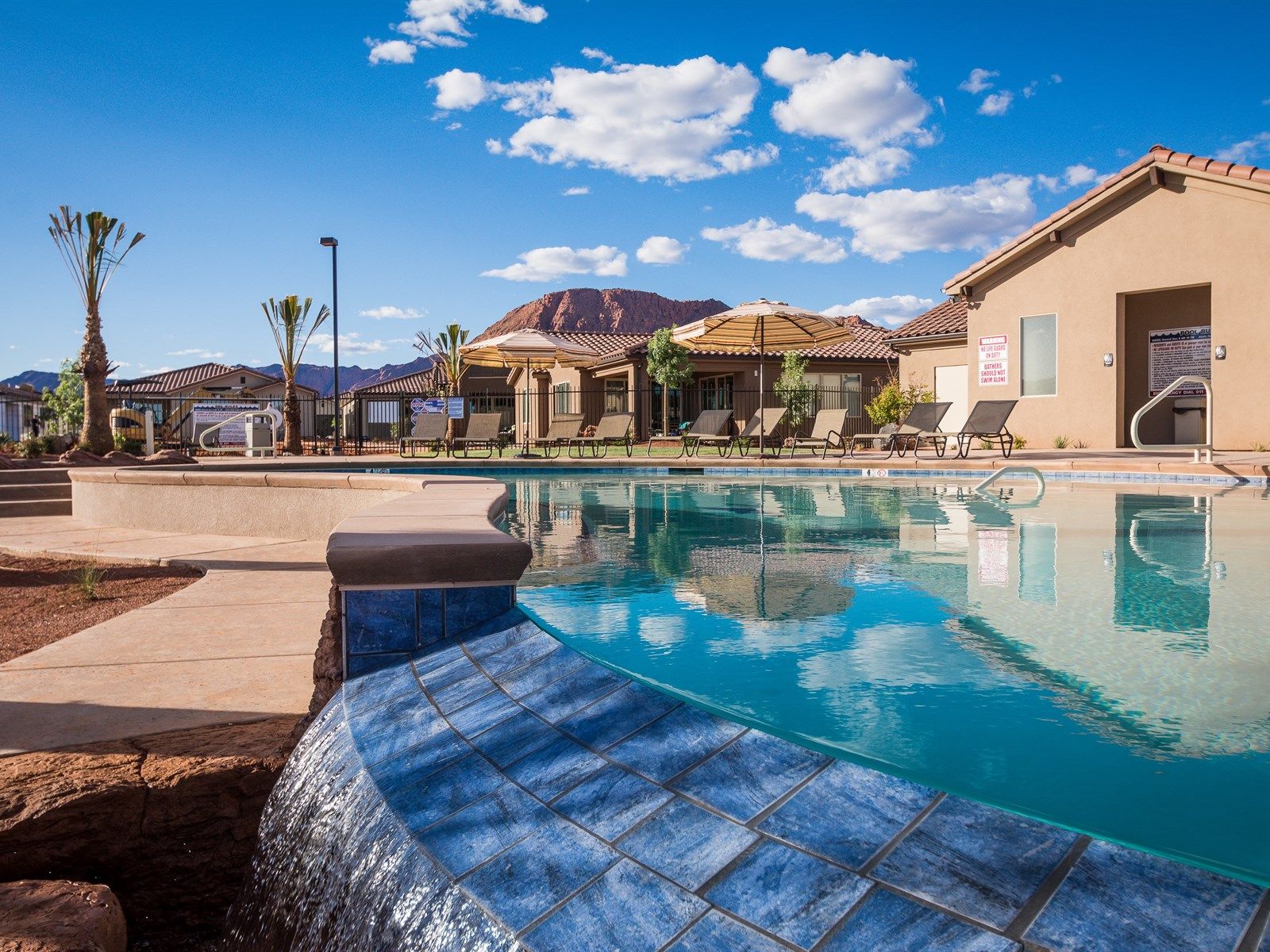 Curved swimming pool with a tiled waterfall feature and surrounding sun loungers
