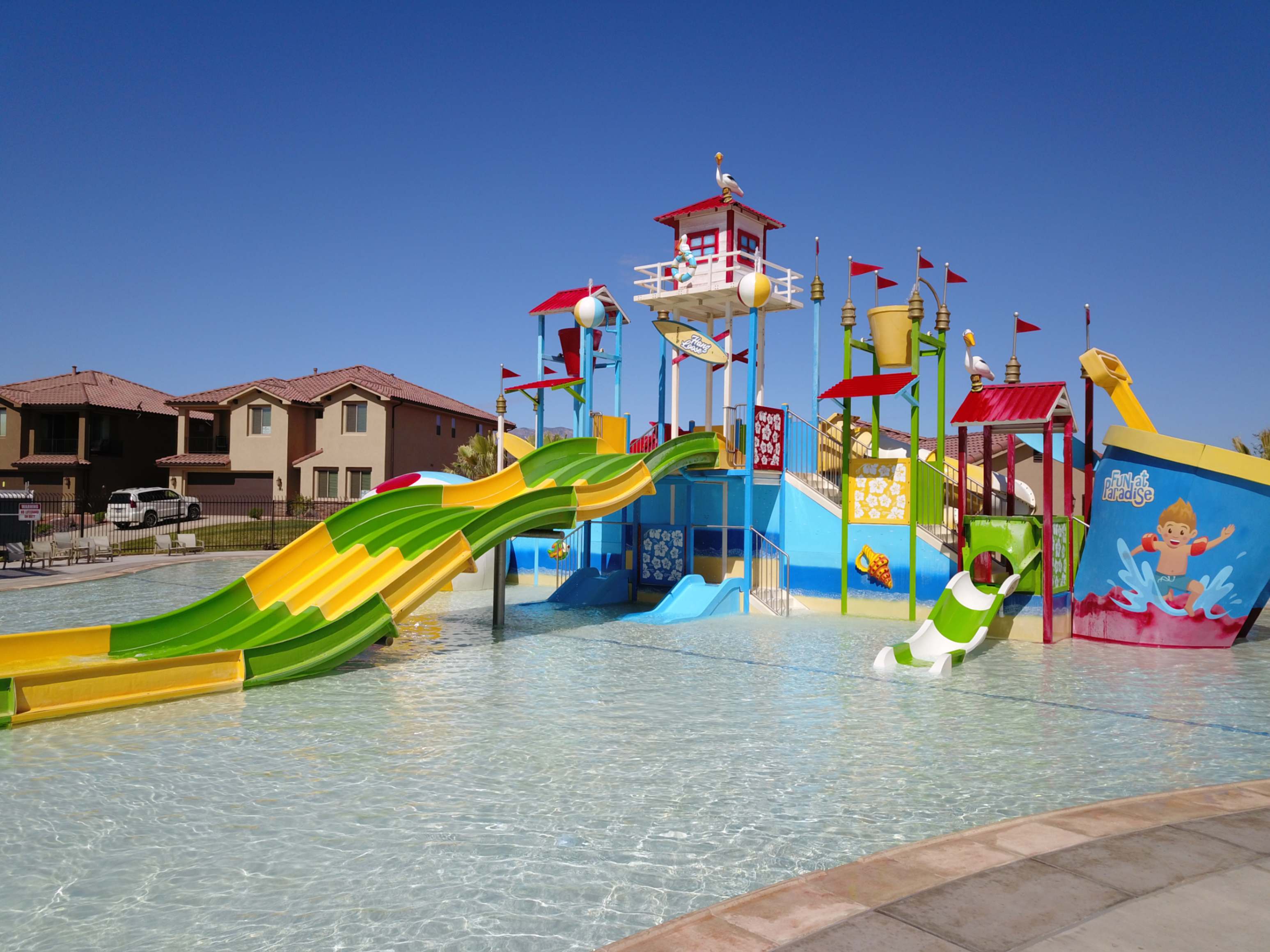 Expansive water park area featuring multiple slides, a water bucket feature, and a central play structure