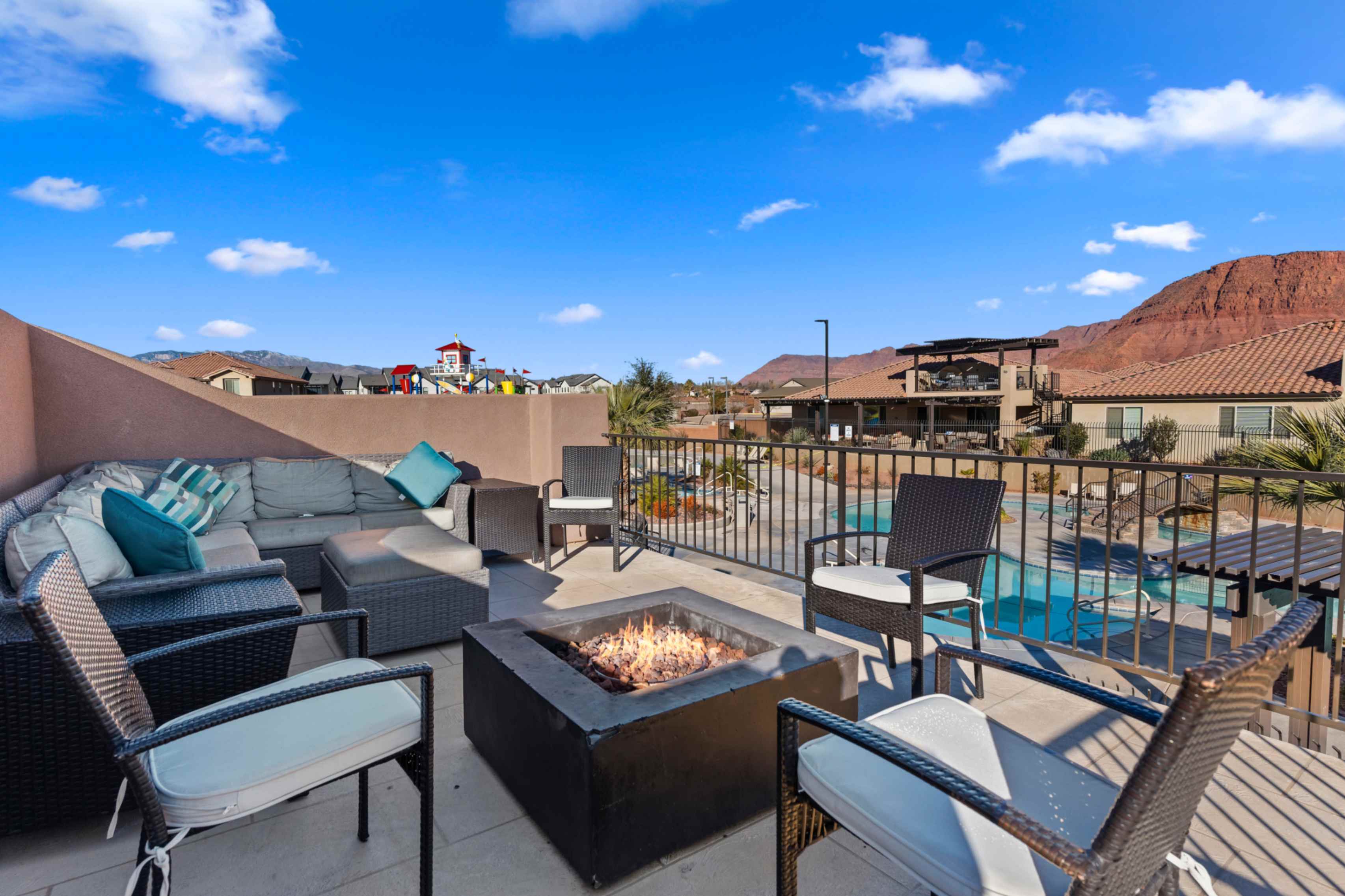 Rooftop patio featuring a built-in fire pit, privacy walls, and a metal railing