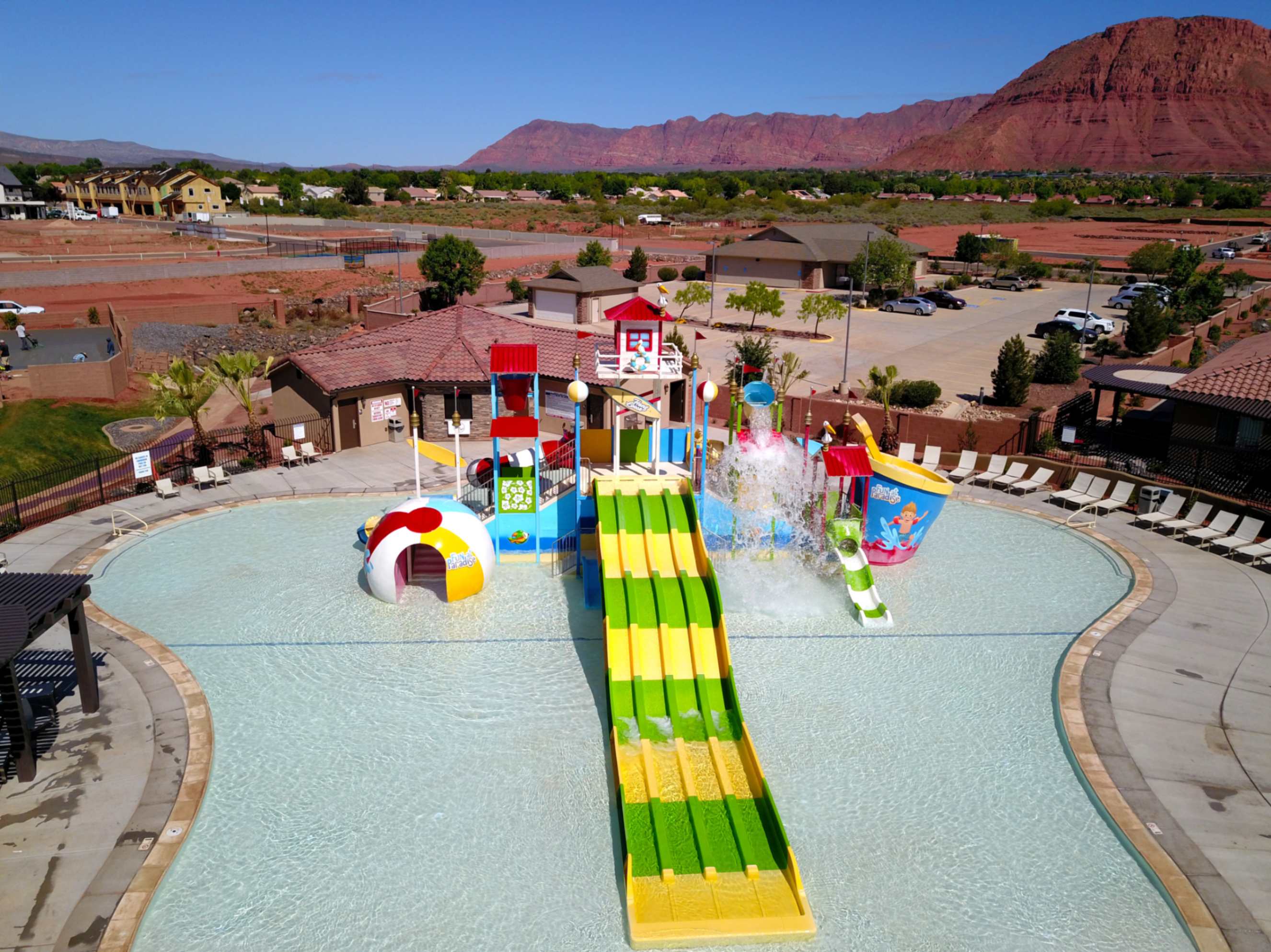 Community aquatic amenity featuring a large swimming pool, multi-lane water slide, and interactive water play structures