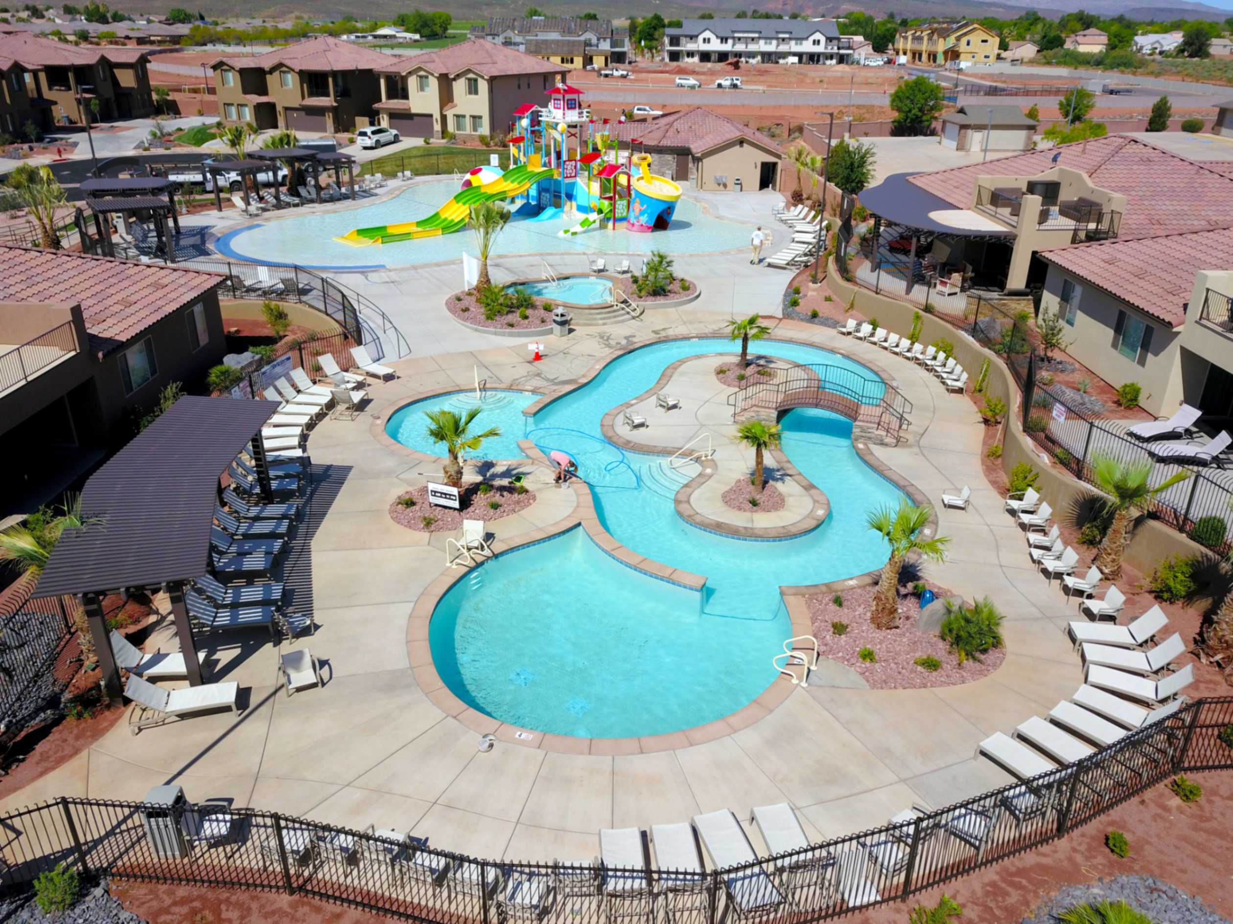 Expansive aquatic recreation area featuring multiple pools, a water slide structure, and a lazy river with bridges