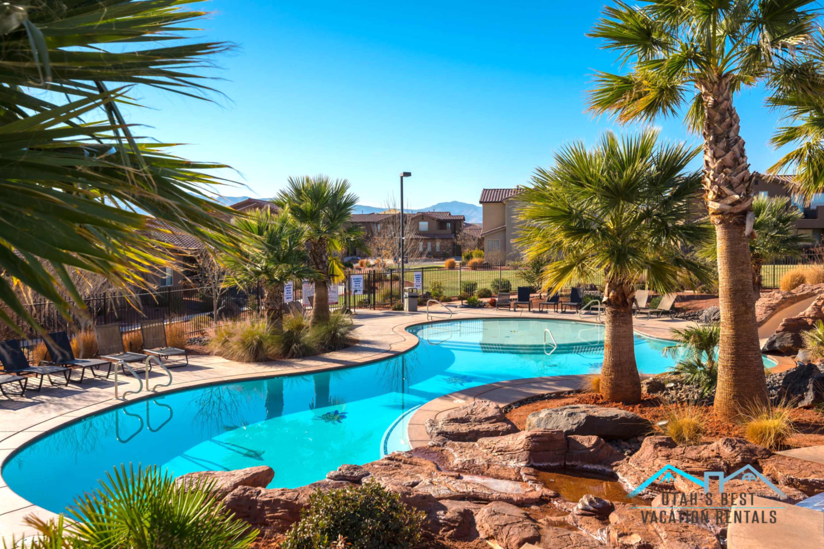 Resort-style pool with a serpentine design, surrounded by mature palm trees and natural rock landscaping