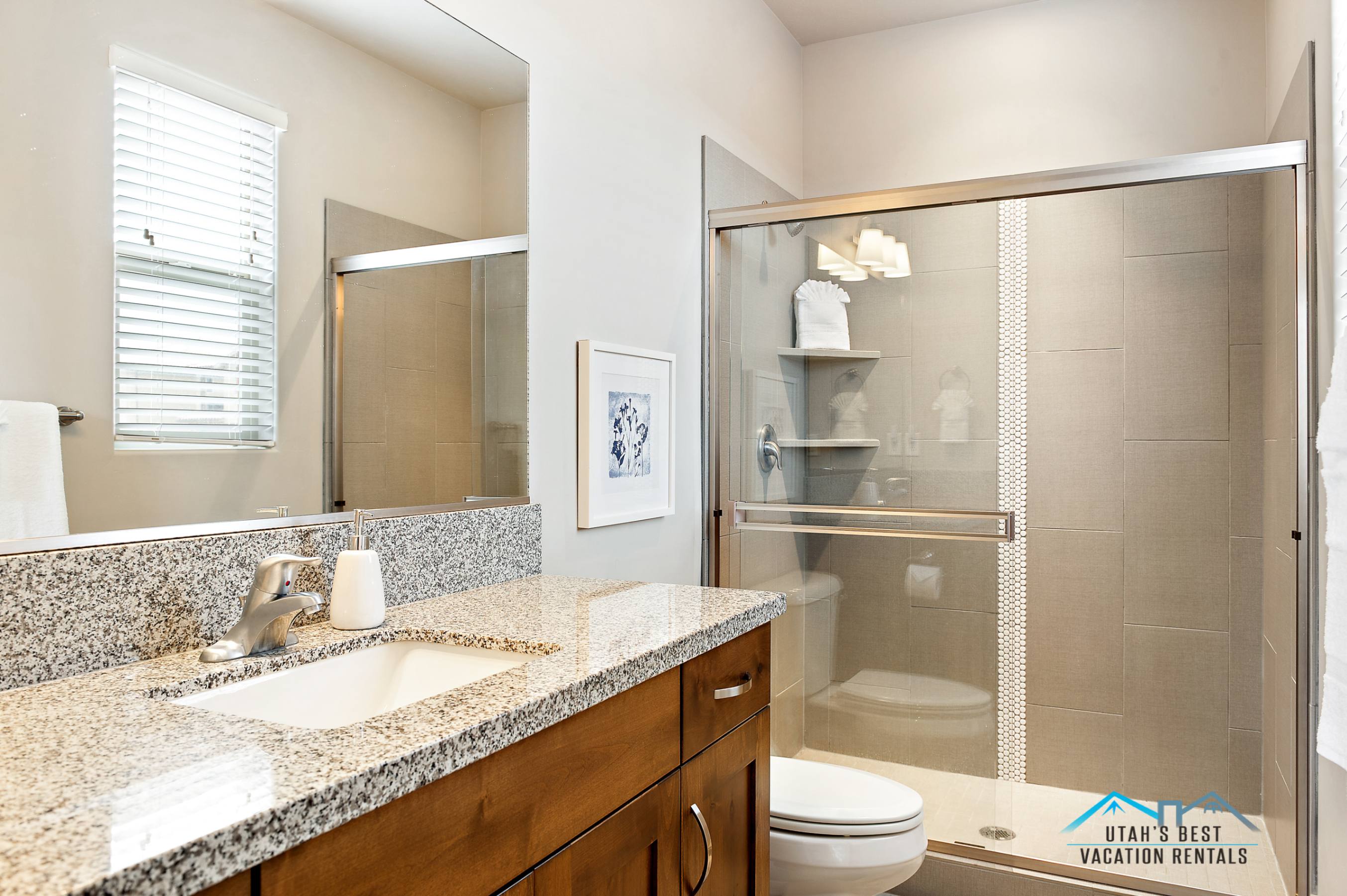 Bathroom featuring a wood-finish vanity with a granite countertop, undermount sink, and brushed nickel faucet