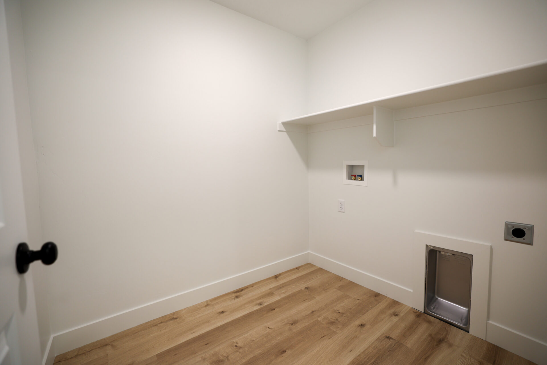 Utility room with wood-finish flooring, white walls, and built-in shelving
