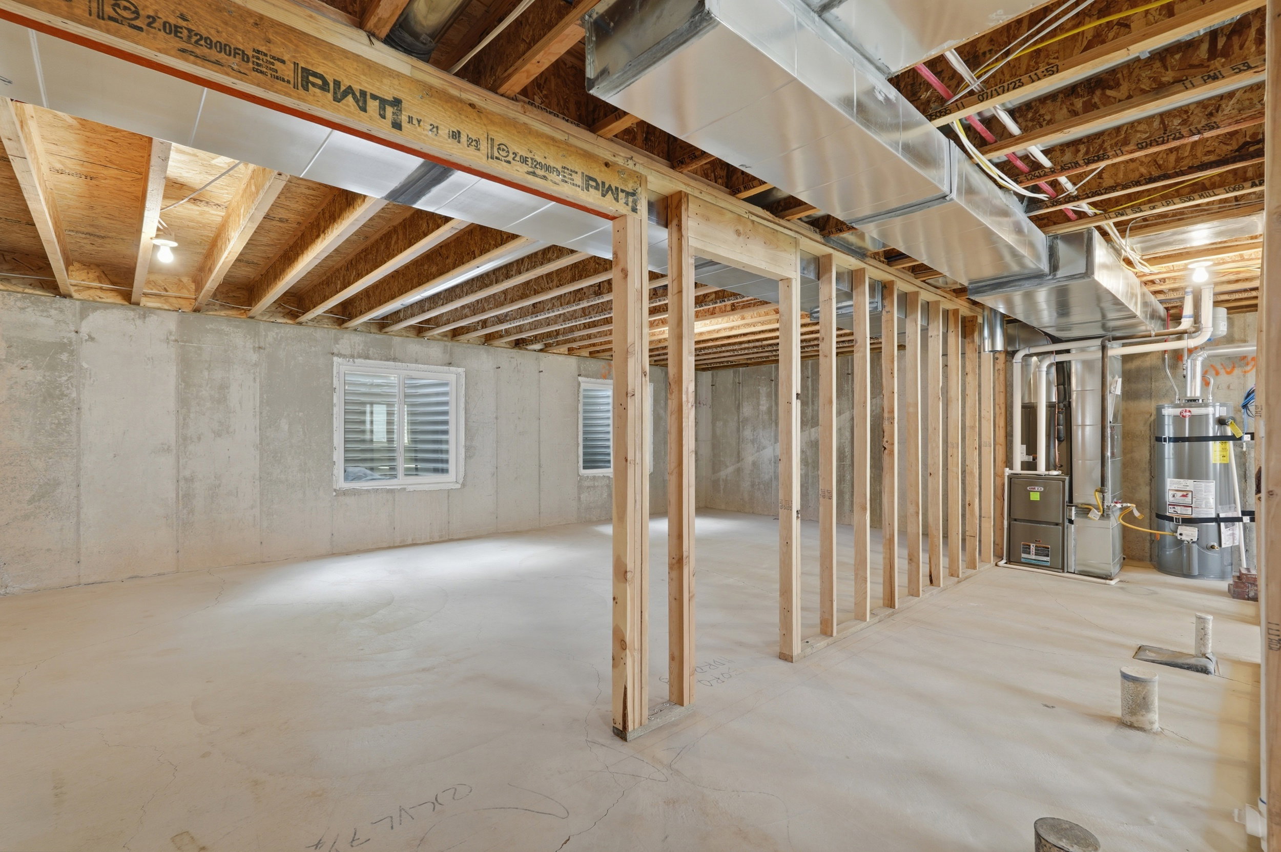 Unfinished basement featuring concrete walls, exposed ceiling joists, two windows with blinds, and existing HVAC ductwork