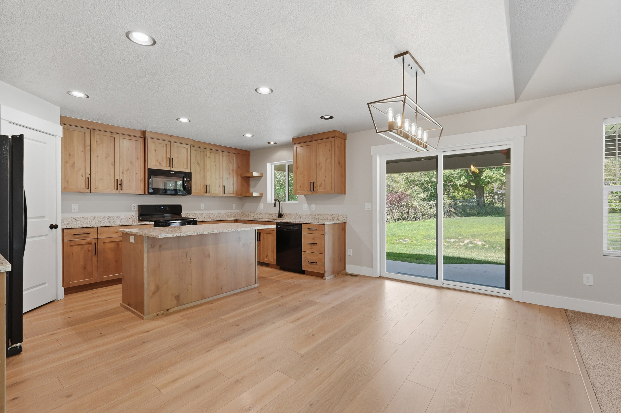 Kitchen featuring wood-finish cabinetry, light-toned countertops, and black appliances