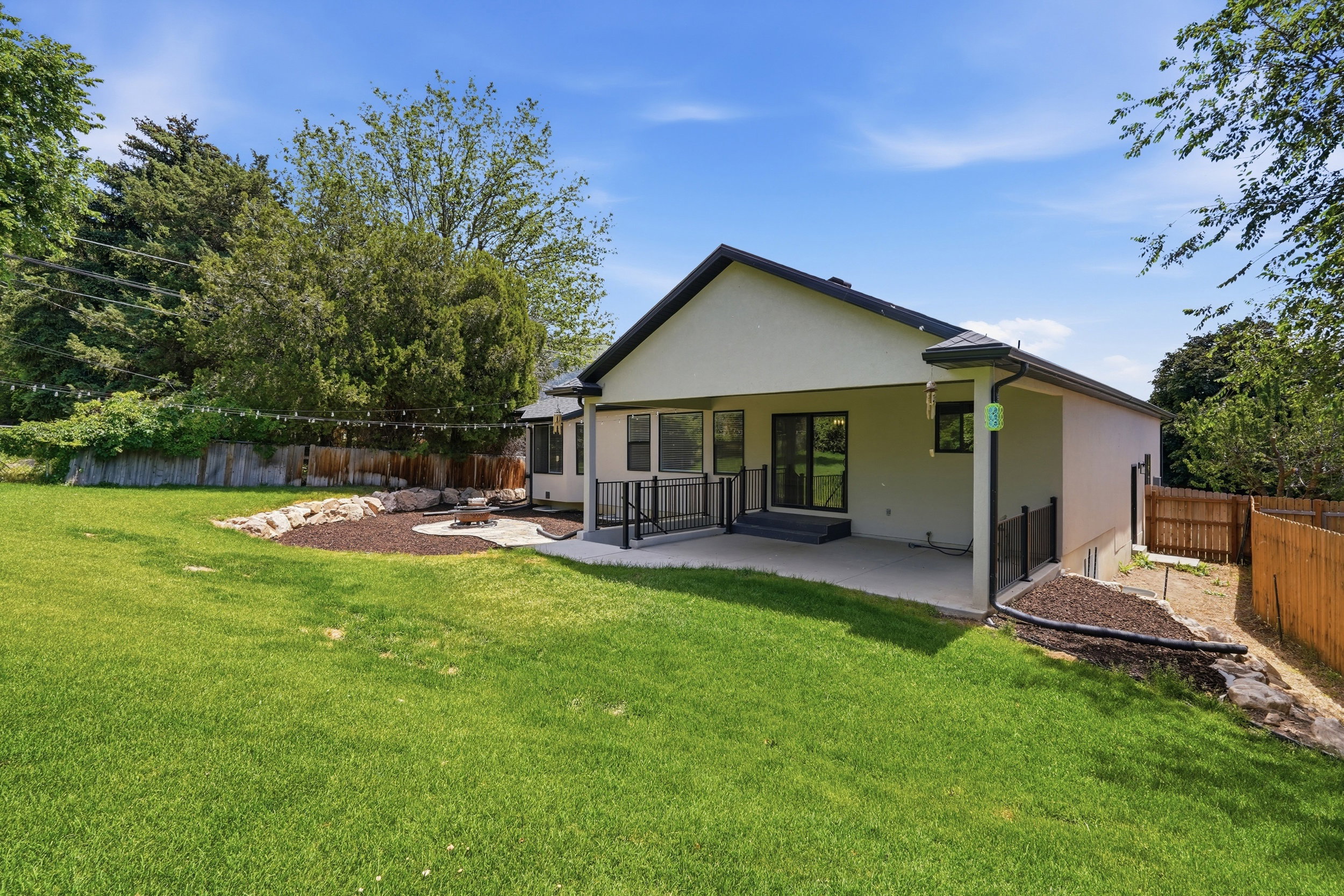 Expansive backyard featuring a manicured lawn, a paved patio, and a dedicated fire pit area