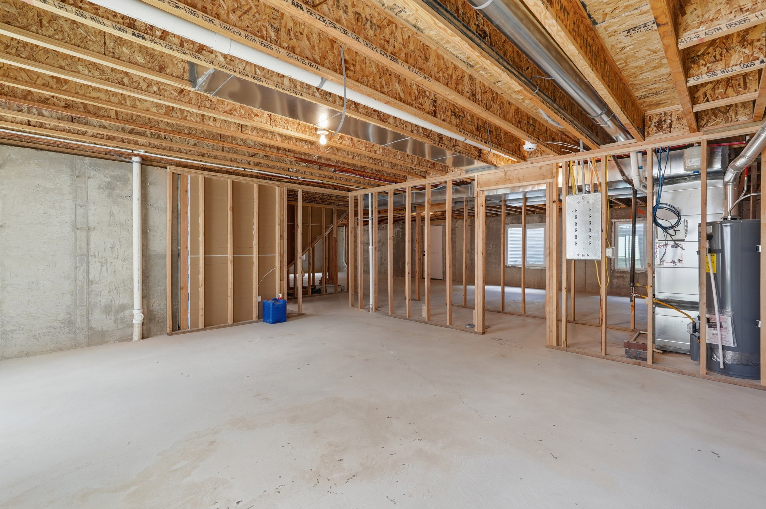 Unfinished basement presenting framed walls, exposed ceiling joists, concrete flooring, and visible utility systems