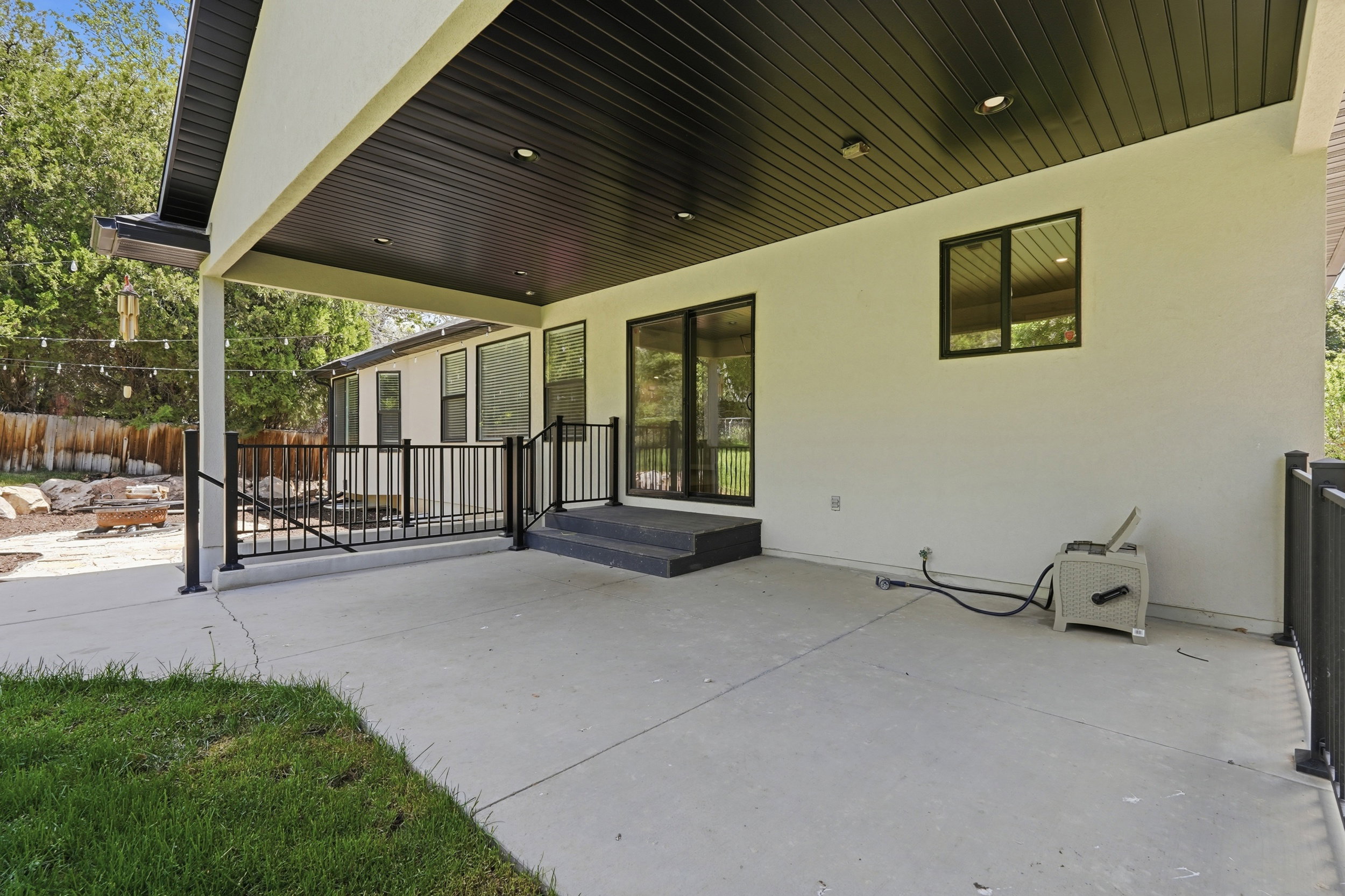 Covered patio featuring a black slatted ceiling with recessed lighting, with access to basement entrance.