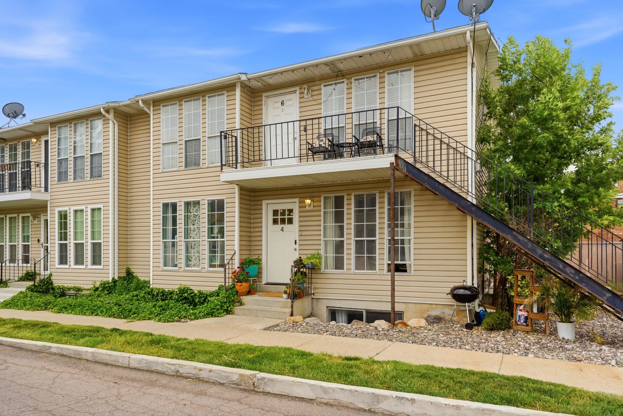 Multi-story property featuring horizontal siding, multiple windows with white grilles, and a main entry door with an overhead light fixture