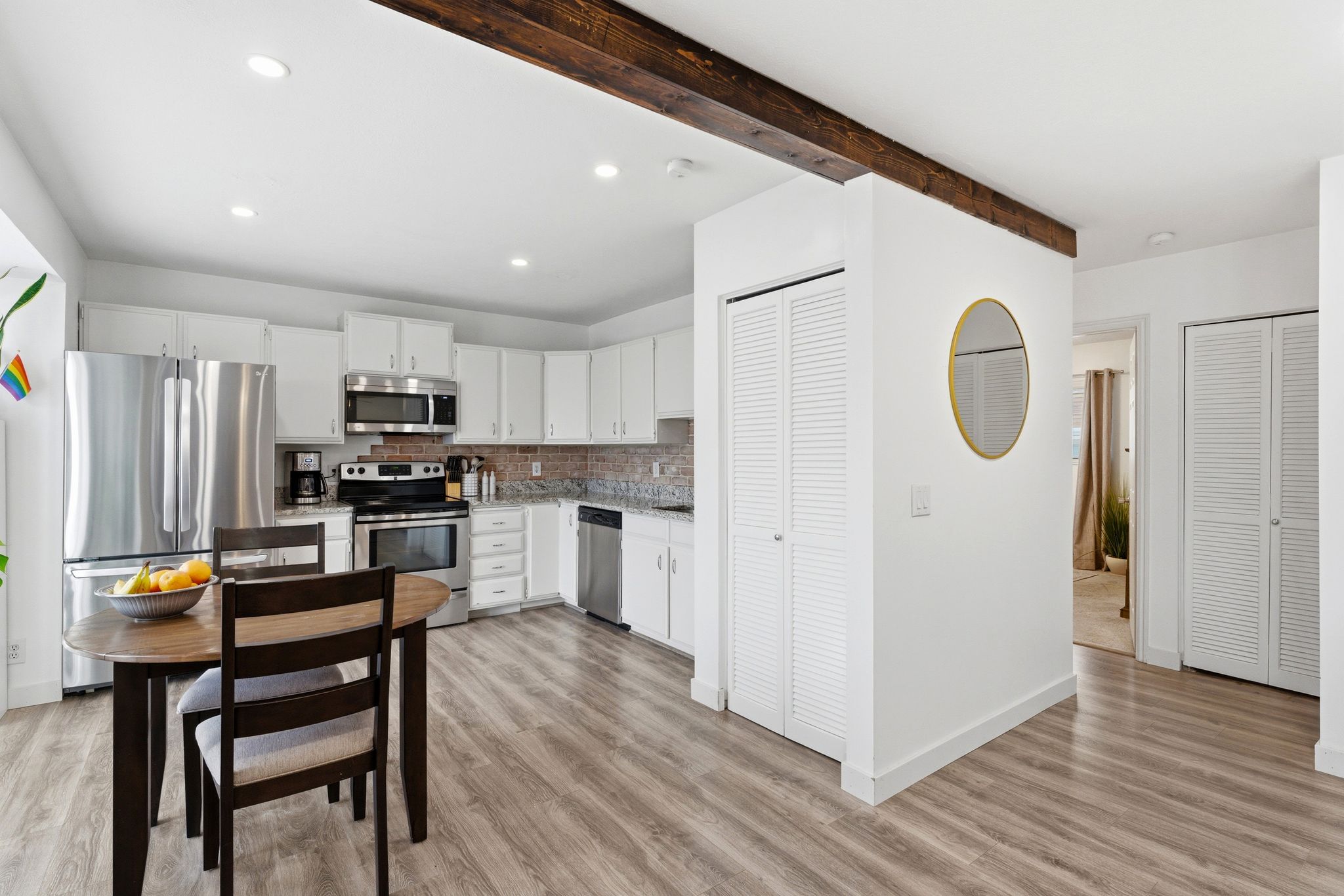 Modern kitchen featuring white cabinetry, stainless steel appliances, and wood-finish flooring