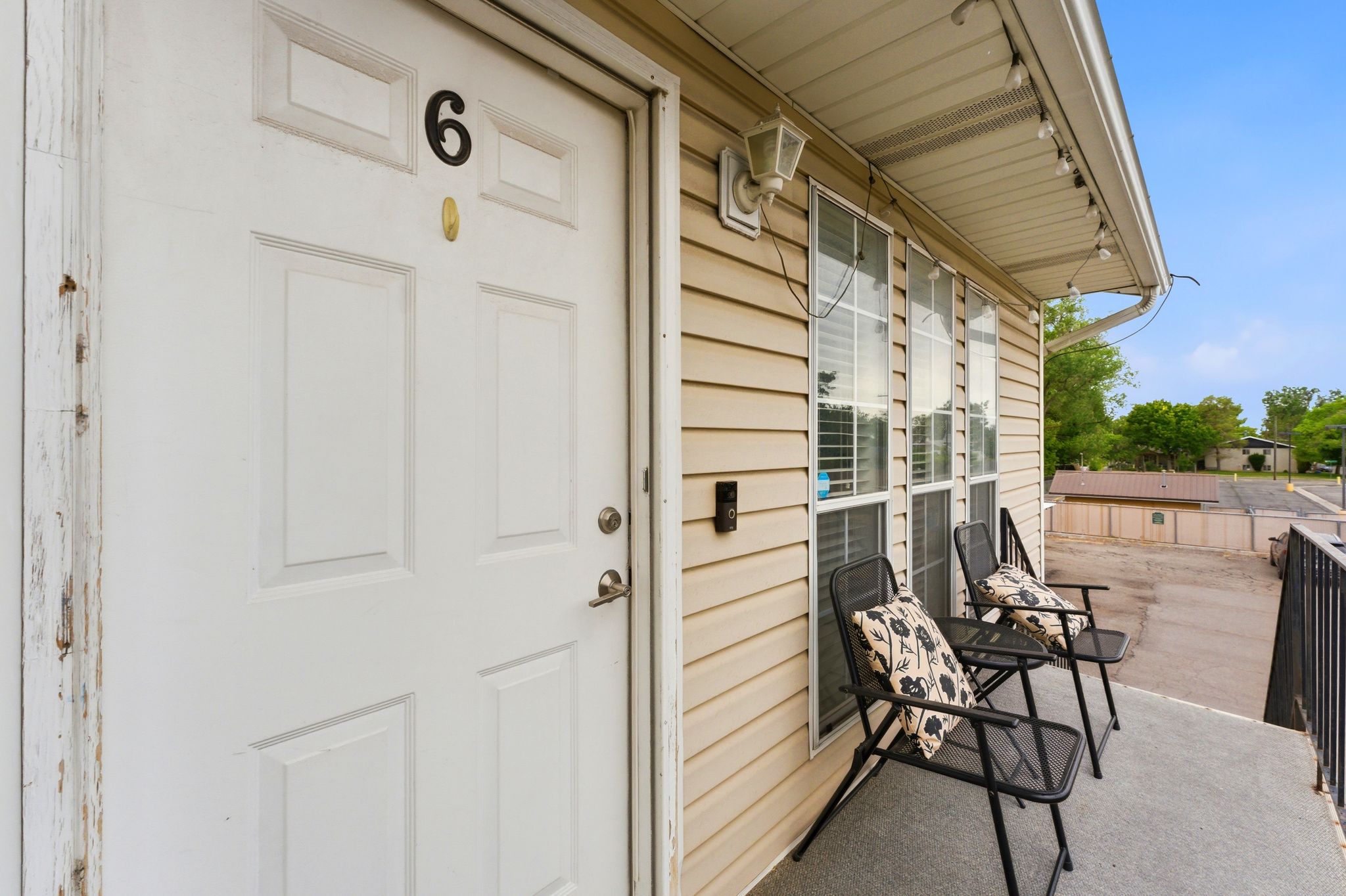 Private balcony entrance featuring light beige siding and a white paneled door