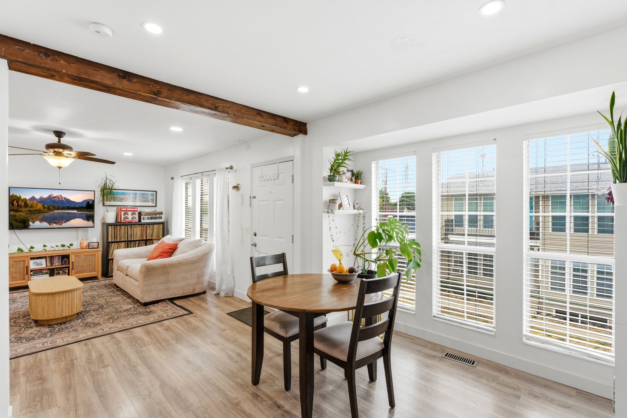 Open-concept living area with wood-finish flooring, recessed lighting, and a prominent exposed beam