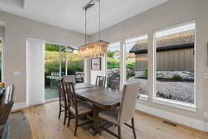 Dining area with wood-finish flooring, featuring a rectangular chandelier and expansive window array